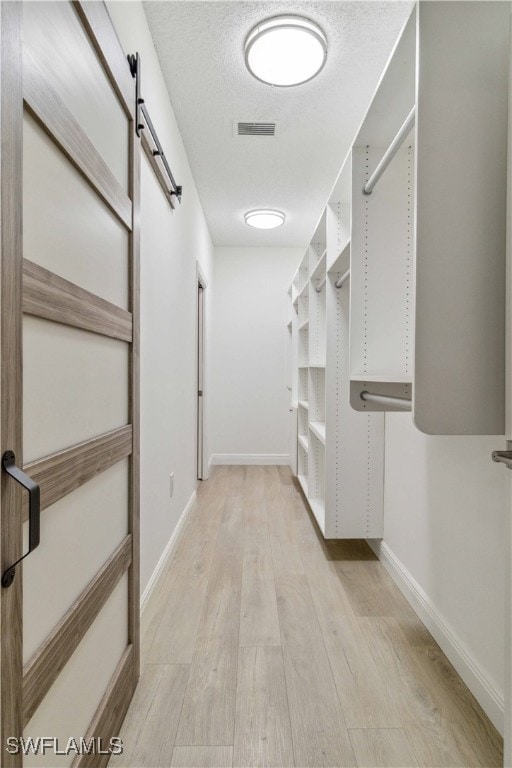 spacious closet featuring a barn door and light hardwood / wood-style flooring