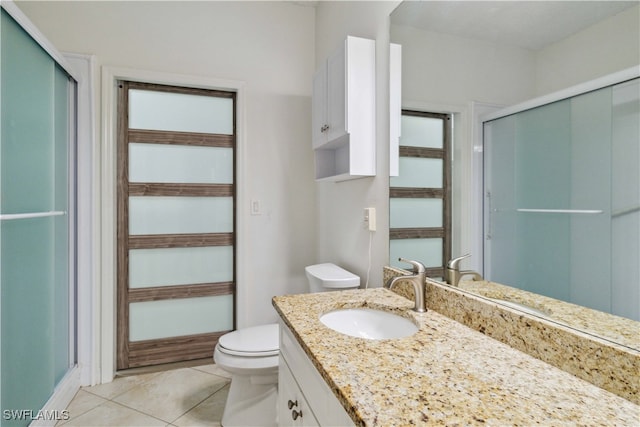 bathroom featuring tile patterned flooring, vanity, toilet, and a shower with door