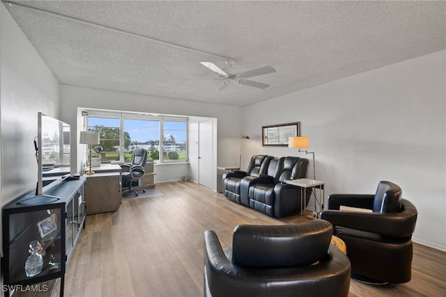 living room featuring light hardwood / wood-style floors, ceiling fan, and a textured ceiling