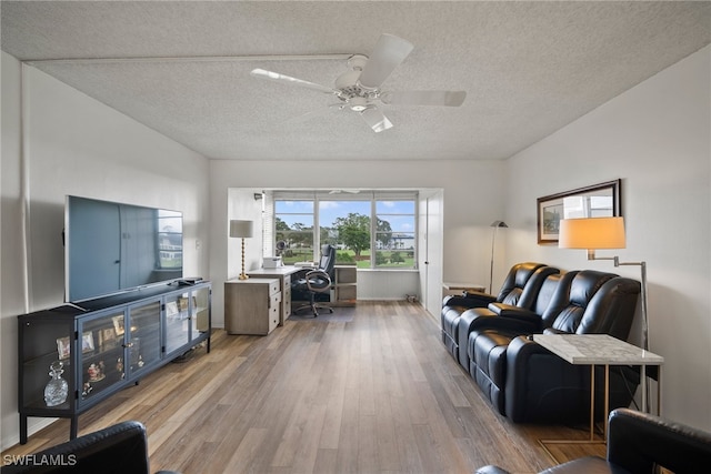 living room featuring light hardwood / wood-style floors, a textured ceiling, and ceiling fan