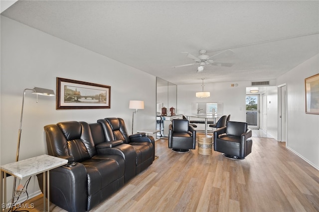 living room with a textured ceiling, light hardwood / wood-style floors, and ceiling fan