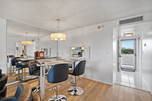 dining area with a textured ceiling and light hardwood / wood-style floors