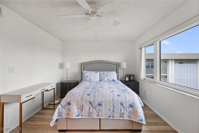 bedroom with a textured ceiling, ceiling fan, and light hardwood / wood-style flooring