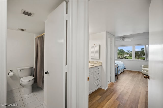 bathroom featuring toilet, vanity, hardwood / wood-style flooring, and ceiling fan