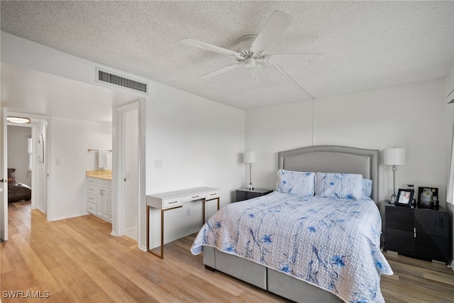 bedroom featuring ensuite bath, ceiling fan, a textured ceiling, and light hardwood / wood-style flooring