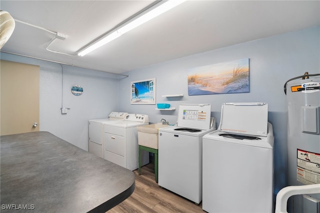 laundry room with sink, wood-type flooring, electric water heater, and washer and dryer