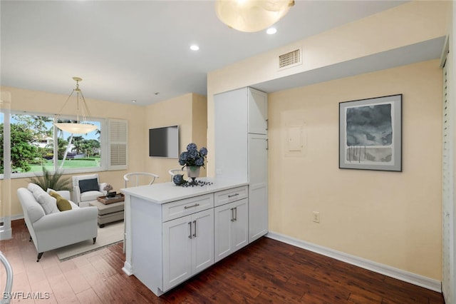 kitchen with white cabinets, hanging light fixtures, dark hardwood / wood-style floors, and kitchen peninsula