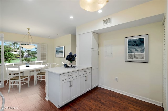 kitchen featuring white cabinetry, kitchen peninsula, dark hardwood / wood-style floors, and hanging light fixtures