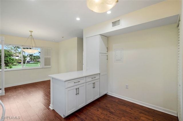 kitchen with dark hardwood / wood-style flooring, kitchen peninsula, hanging light fixtures, and white cabinets