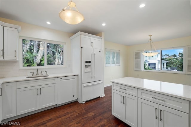 kitchen with white cabinets, sink, dark hardwood / wood-style floors, white appliances, and decorative light fixtures