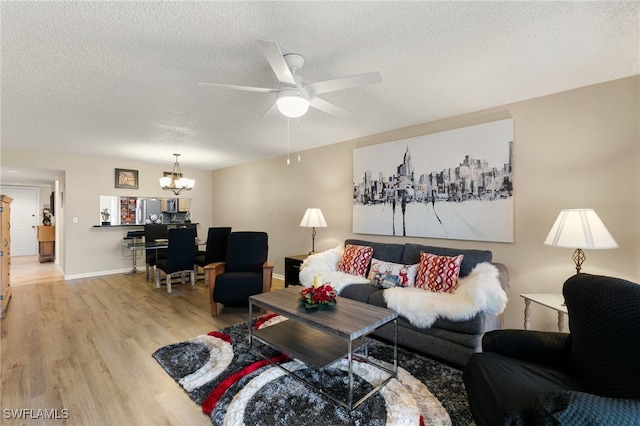 living room with a textured ceiling, ceiling fan with notable chandelier, and light hardwood / wood-style flooring