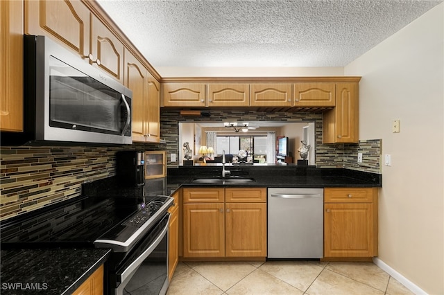 kitchen with dark stone counters, sink, tasteful backsplash, light tile patterned flooring, and stainless steel appliances