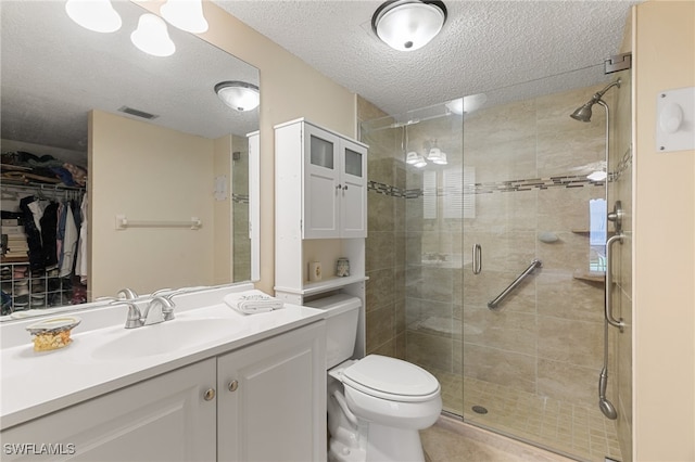 bathroom with vanity, toilet, an enclosed shower, and a textured ceiling