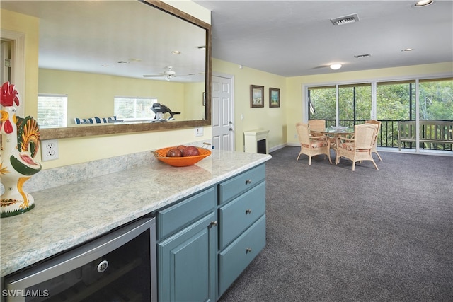 kitchen featuring ceiling fan, a healthy amount of sunlight, beverage cooler, and dark colored carpet