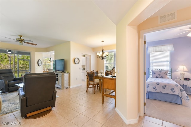 living room with light tile patterned floors, a healthy amount of sunlight, and ceiling fan with notable chandelier