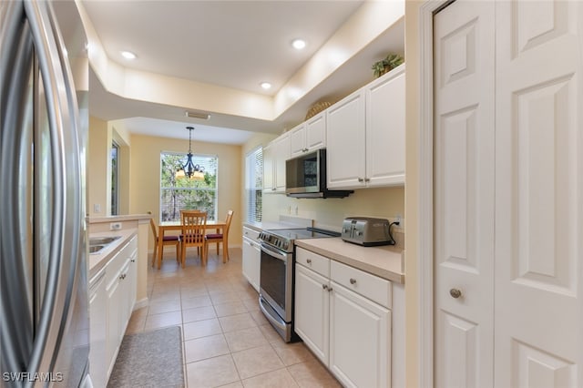 kitchen with stainless steel appliances, hanging light fixtures, light tile patterned floors, a chandelier, and white cabinetry