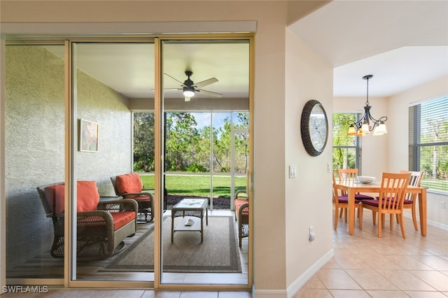 doorway to outside featuring light tile patterned flooring and ceiling fan with notable chandelier