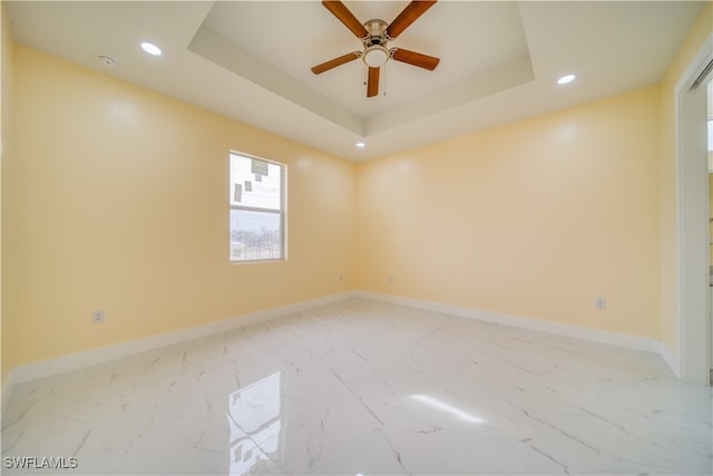 spare room with ceiling fan and a raised ceiling