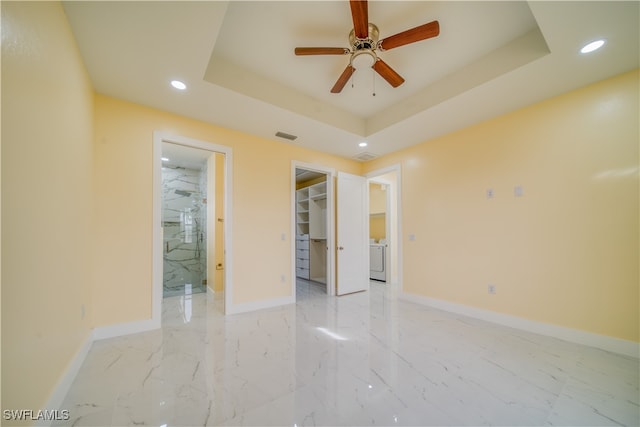 spare room featuring washer / clothes dryer, ceiling fan, and a raised ceiling