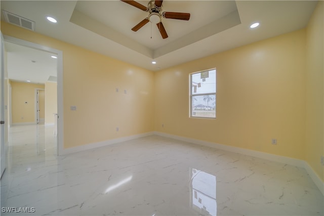 empty room featuring a tray ceiling and ceiling fan