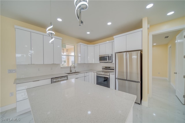 kitchen featuring light stone counters, white cabinetry, pendant lighting, and appliances with stainless steel finishes