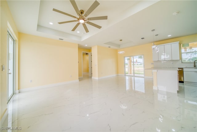 spare room with a tray ceiling, sink, and ceiling fan