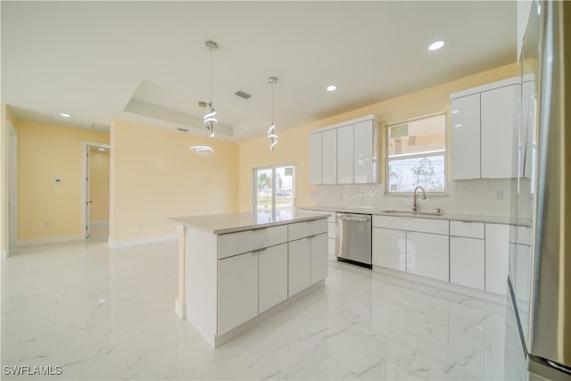 kitchen featuring backsplash, decorative light fixtures, white cabinets, stainless steel dishwasher, and a center island