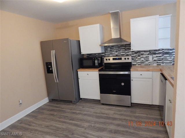 kitchen with dark hardwood / wood-style flooring, wall chimney range hood, appliances with stainless steel finishes, and white cabinets