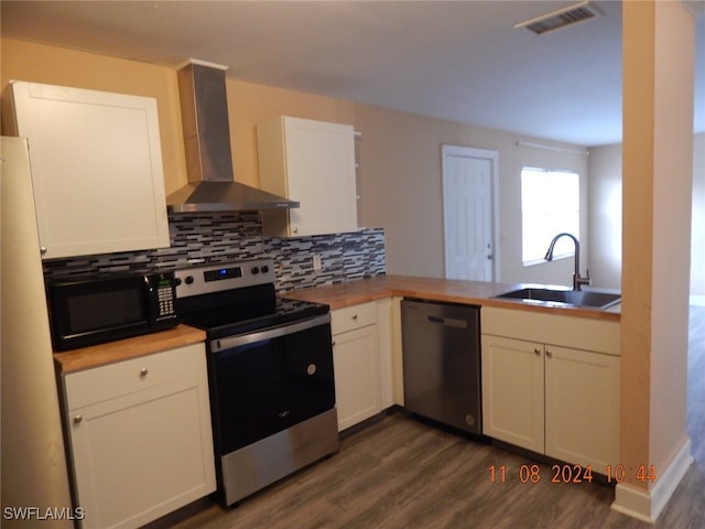 kitchen with stainless steel appliances, white cabinetry, sink, kitchen peninsula, and wall chimney exhaust hood