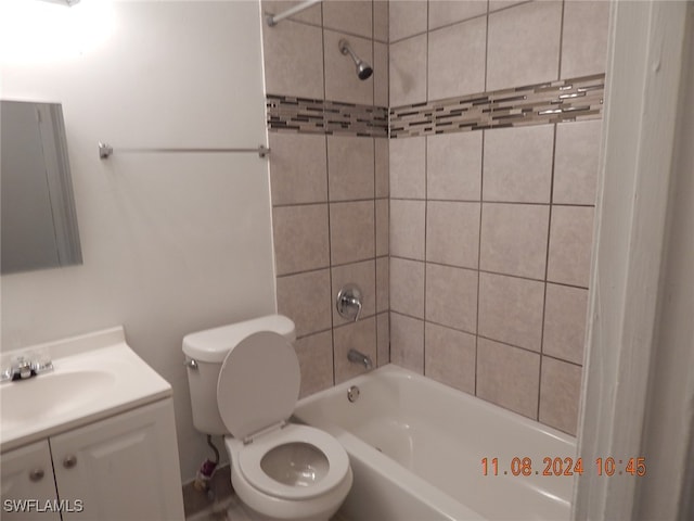 full bathroom with tiled shower / bath, vanity, and toilet