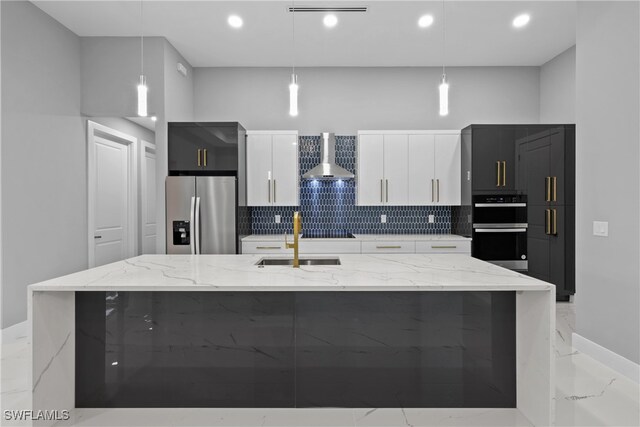 kitchen featuring black appliances, decorative light fixtures, an island with sink, and white cabinets