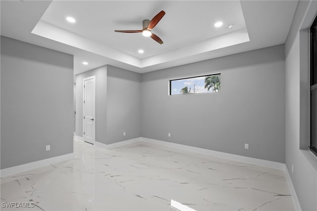 unfurnished room with ceiling fan and a raised ceiling