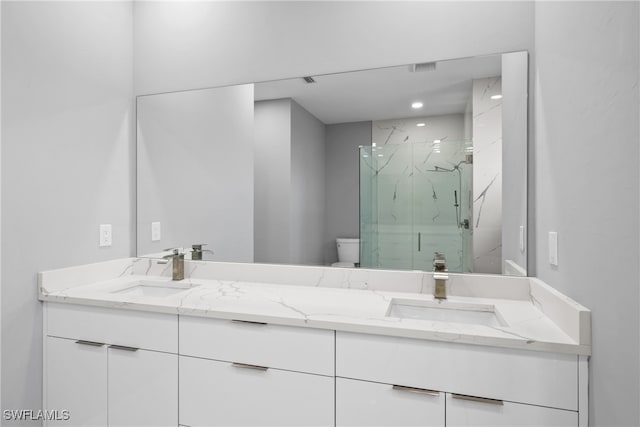 bathroom featuring toilet, vanity, and a shower with shower door