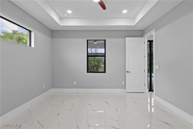 empty room featuring a tray ceiling and ceiling fan