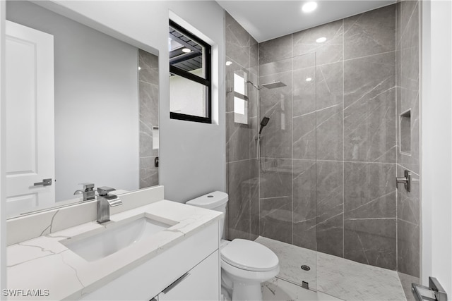 bathroom with vanity, toilet, and a tile shower