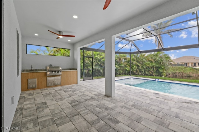 view of swimming pool featuring glass enclosure, a patio, sink, area for grilling, and ceiling fan