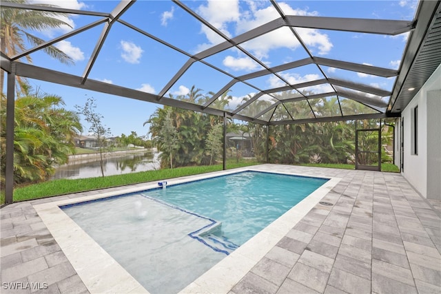 view of pool with glass enclosure, a water view, and a patio