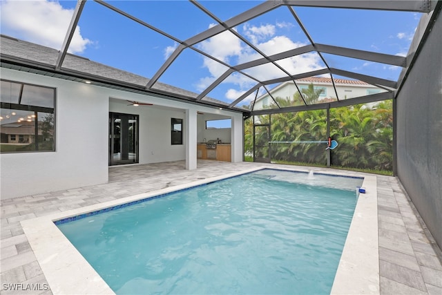 view of swimming pool featuring a patio, glass enclosure, ceiling fan, and pool water feature