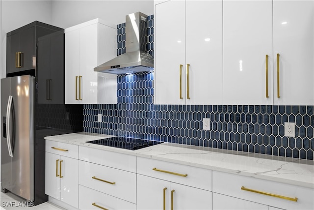 kitchen with black electric cooktop, white cabinets, stainless steel fridge with ice dispenser, wall chimney range hood, and light stone countertops