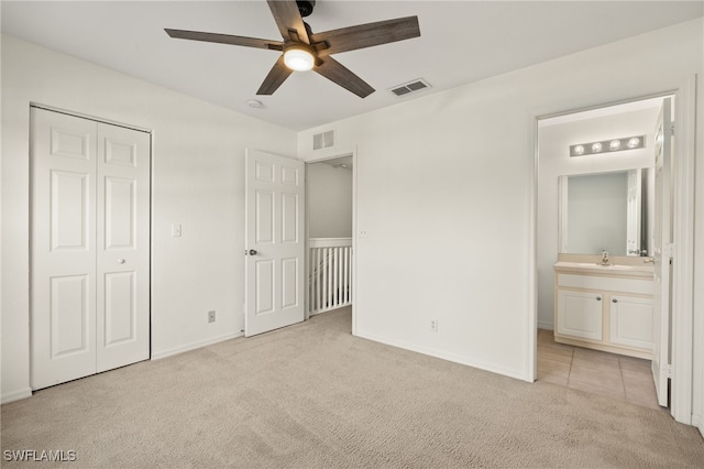 unfurnished bedroom with ensuite bath, ceiling fan, sink, light carpet, and a closet