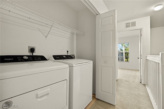 washroom with separate washer and dryer and light colored carpet