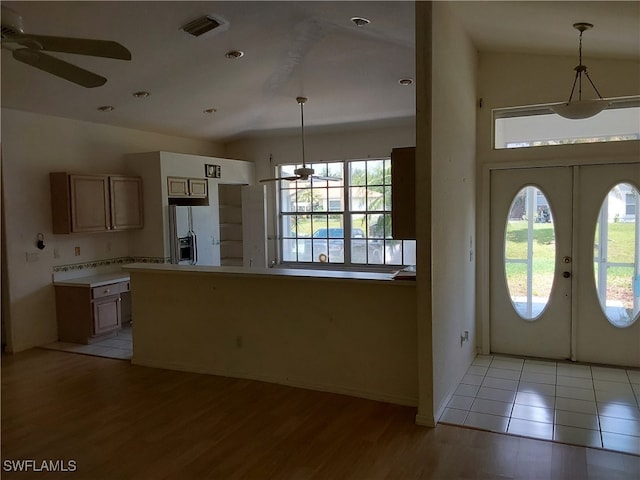 interior space with french doors, white fridge with ice dispenser, hanging light fixtures, and light hardwood / wood-style flooring