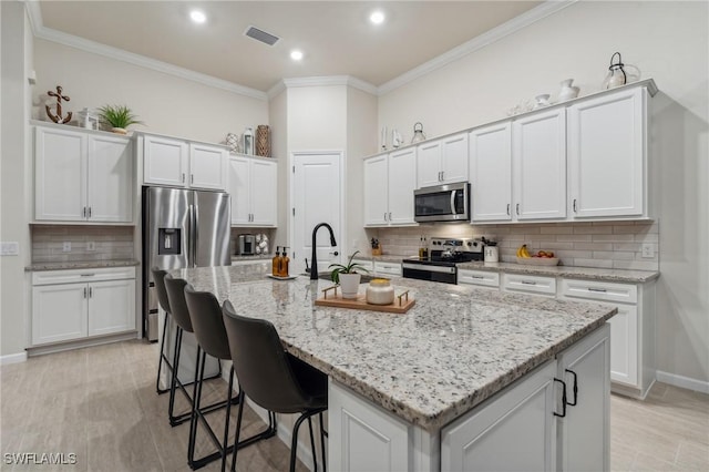 kitchen with white cabinetry, appliances with stainless steel finishes, and ornamental molding