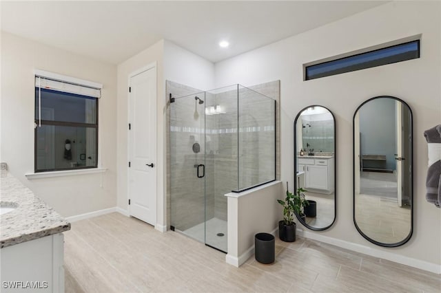 bathroom with vanity, a shower stall, recessed lighting, and baseboards