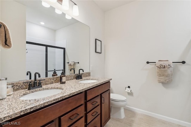 bathroom featuring a sink, toilet, double vanity, and a shower stall