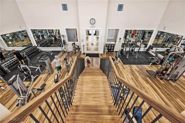 exercise room featuring visible vents, french doors, a towering ceiling, and wood finished floors