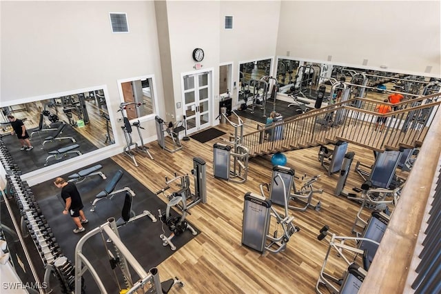 workout area with a high ceiling, wood finished floors, and visible vents