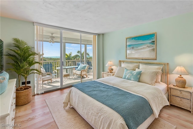 bedroom featuring light wood-type flooring, floor to ceiling windows, and access to exterior