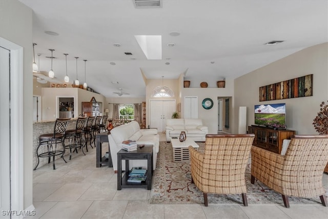 tiled living room with ceiling fan and vaulted ceiling with skylight