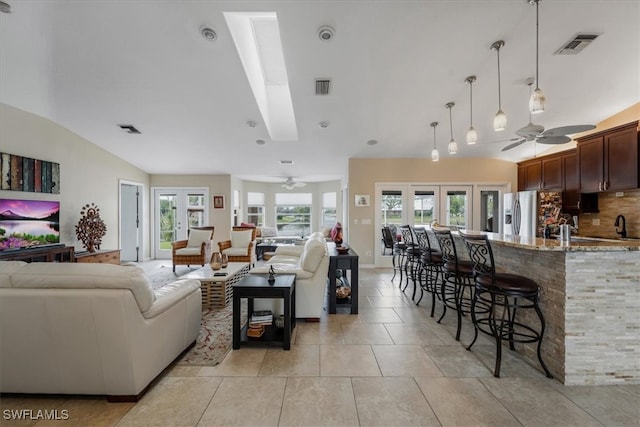 tiled living room with ceiling fan, a healthy amount of sunlight, and lofted ceiling with skylight